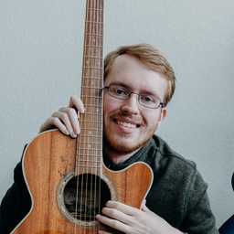 Dylan Perkins smiling with a guitar.